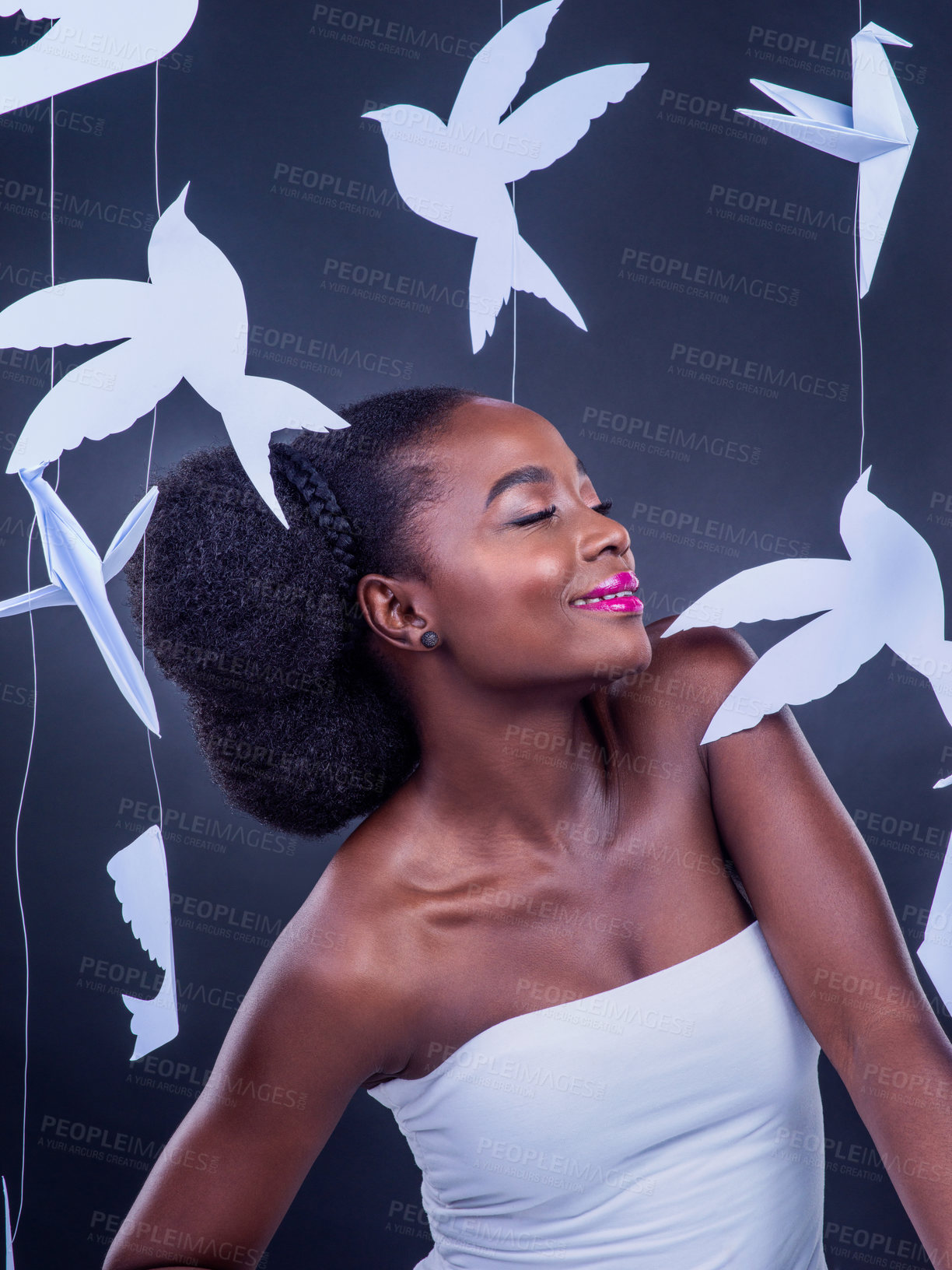 Buy stock photo Studio shot of a beautiful young woman posing with paper birds against a black background