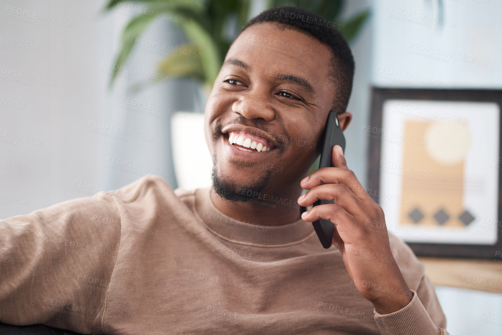 Buy stock photo Black man, phone call and relax in home, house and living room, mobile communication and contact social network. Happy young african guy talking on smartphone, conversation and cellphone technology 