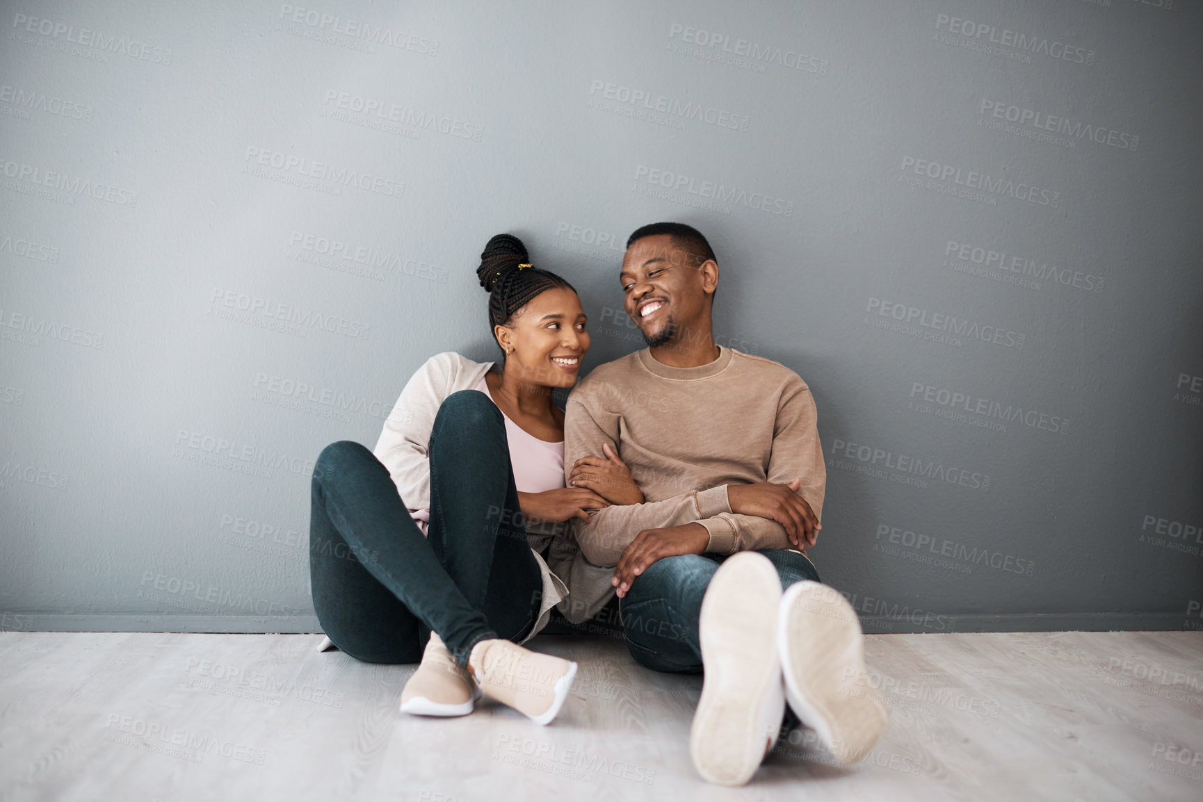 Buy stock photo Homeowner, love and beginning with a black couple sitting together in their new home on a gray wall background. Real estate, room and mortgage with a man and woman on the floor after moving house