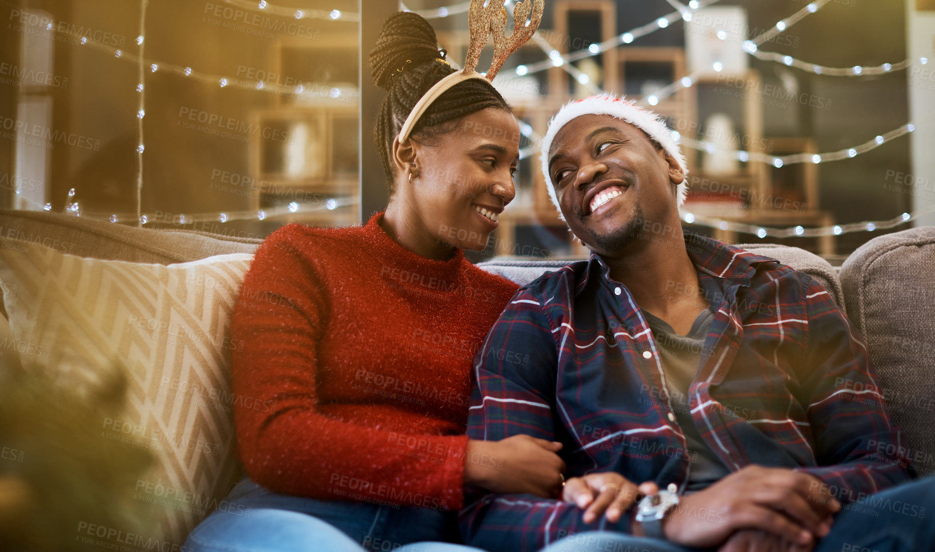 Buy stock photo Couple, living room and Christmas love of a celebration on a sofa with bonding and care. Black people smile in a house for holiday to celebrate winter happiness together with partner and funny hats