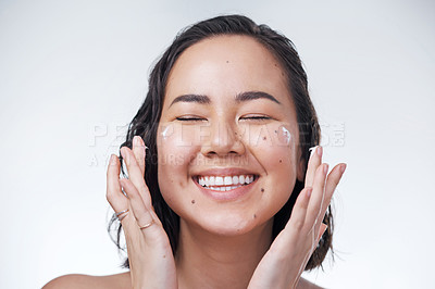 Buy stock photo Cropped shot of a beautiful young woman applying moisturiser to her face