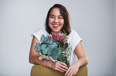 Buy stock photo Shot of a beautiful young woman posing with a bouquet against a grey background