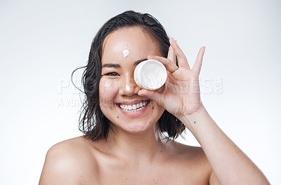 Buy stock photo Shot of a beautiful young woman holding up a pot of moisturiser