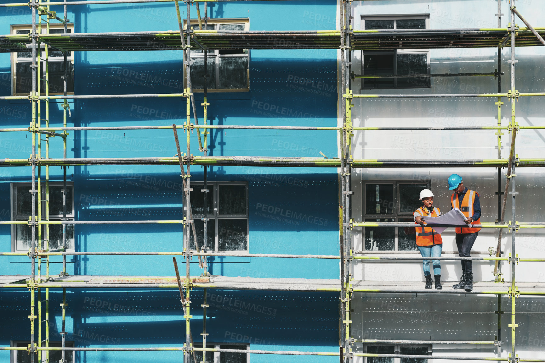 Buy stock photo Shot of a young man and woman going over building plans at a construction site