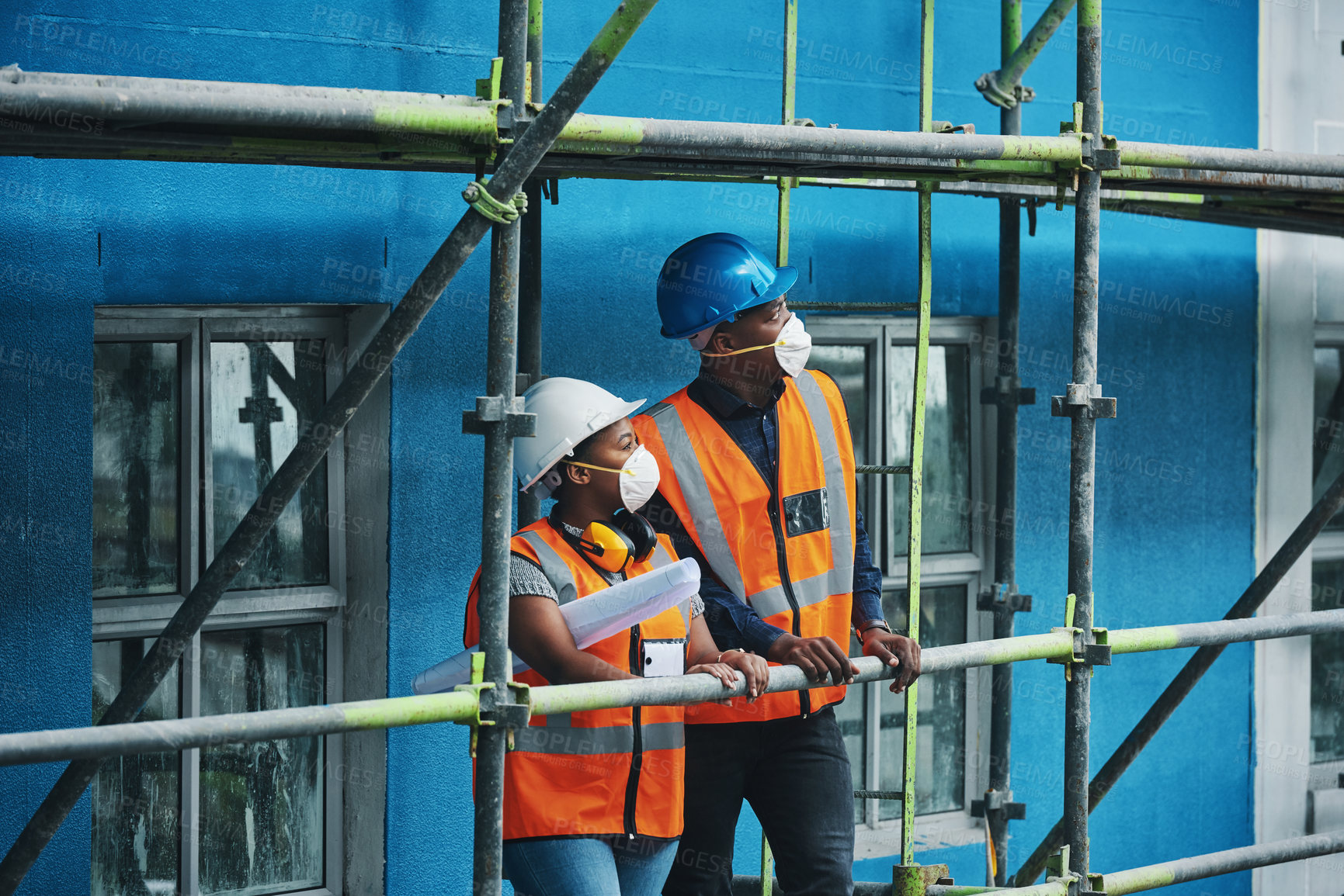 Buy stock photo Teamwork, construction and people at site with mask for collaboration, safety and architecture. Property developer, man and woman contractor on scaffolding with blueprint for civil engineering plan