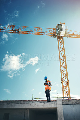 Buy stock photo Shot of a young man using a smartphone while working at a construction site