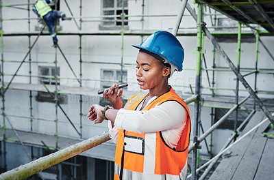 Buy stock photo Shot of a young woman using a smartphone and checking the time while working at a construction site