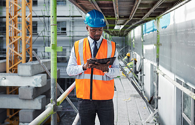 Buy stock photo Shot of a young man using a digital tablet while working at a construction site