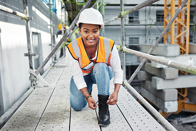 Buy stock photo Shot of a young woman tying the shoelaces on her boots while working at a construction site