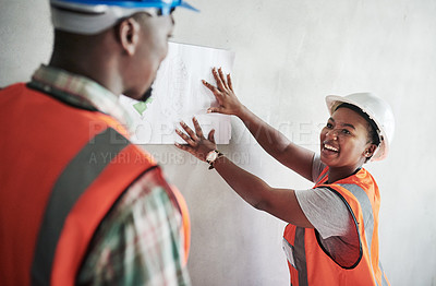 Buy stock photo Shot of a young man and woman going over building plans at a construction site