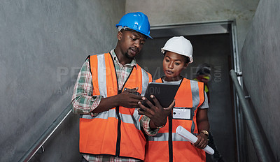 Buy stock photo Shot of a young man and woman using a digital tablet while working at a construction site