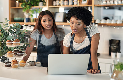 Buy stock photo Shot of two young women working together on a laptop in a cafe