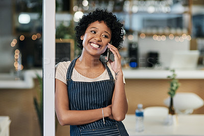 Buy stock photo Shot of a young woman talking on a cellphone while working in a cafe