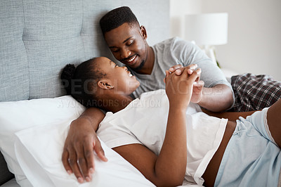 Buy stock photo Shot of an affectionate young couple relaxing on their bed together at home