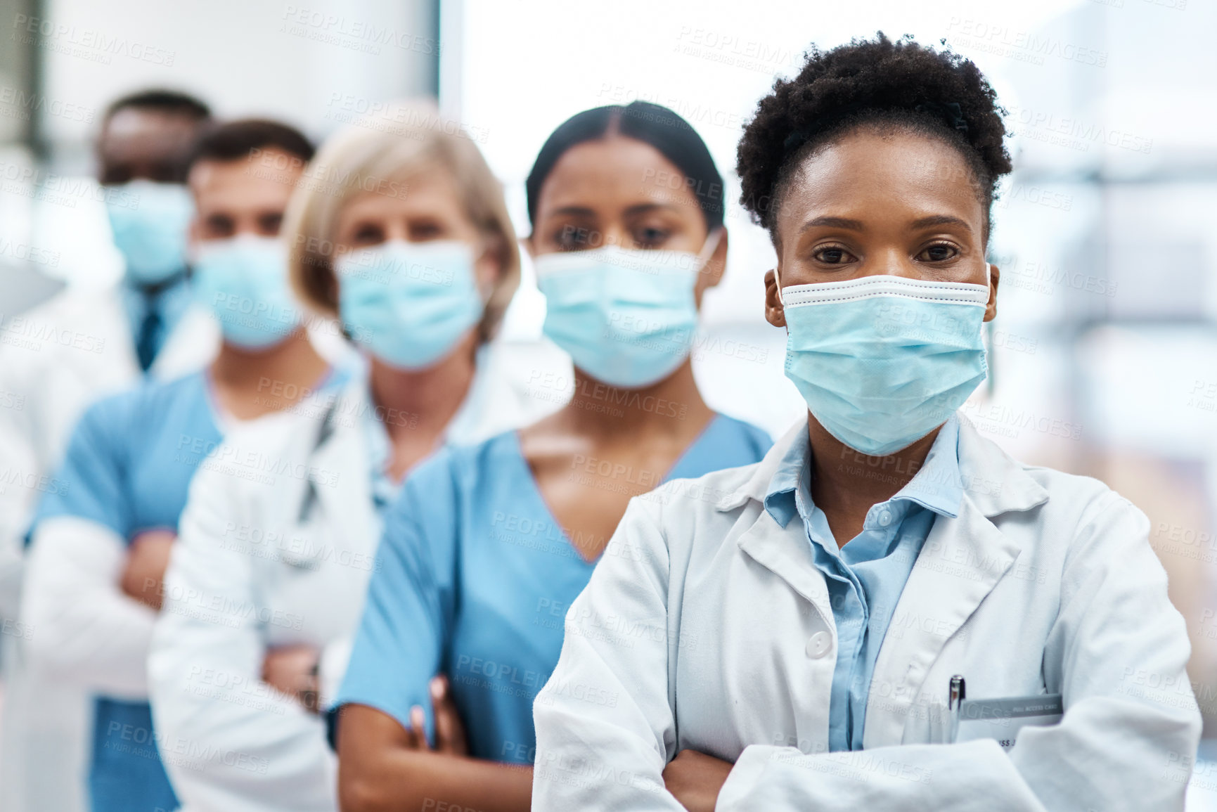 Buy stock photo Portrait of a group of medical practitioners wearing face masks while standing together in a hospital