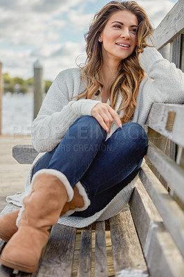 Buy stock photo Shot of a beautiful young woman relaxing on a bench outdoors