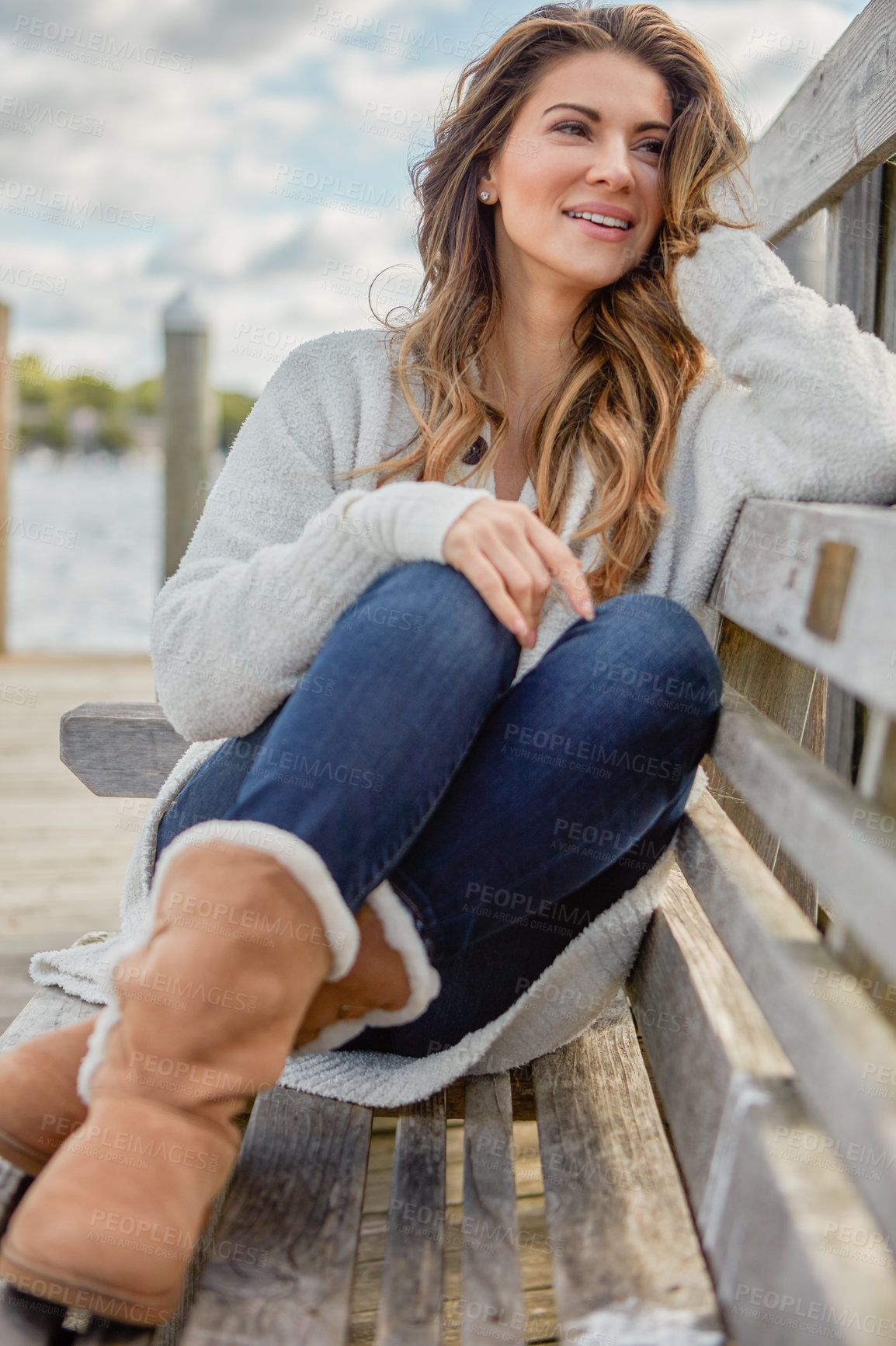 Buy stock photo Shot of a beautiful young woman relaxing on a bench outdoors