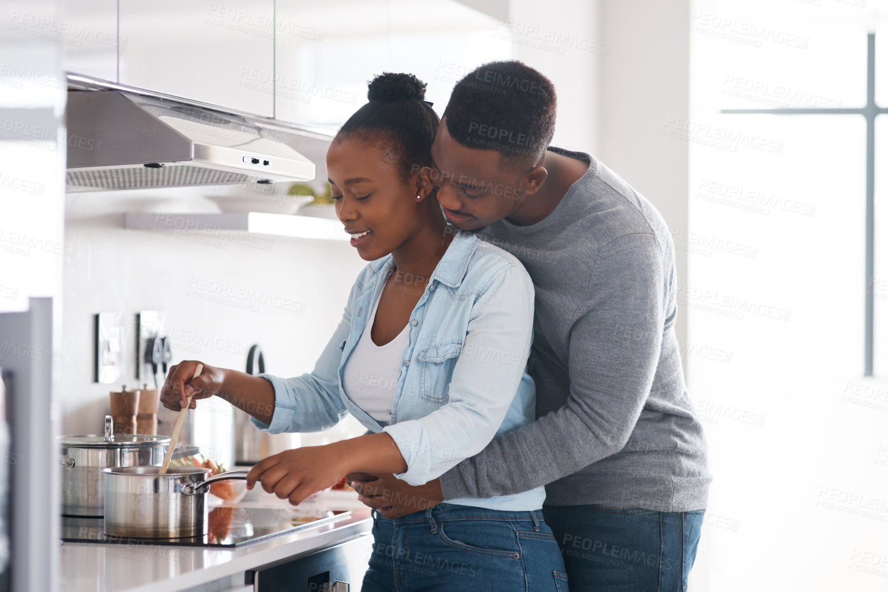 Buy stock photo Shot of a man embracing his wife from behind while she's busy cooking