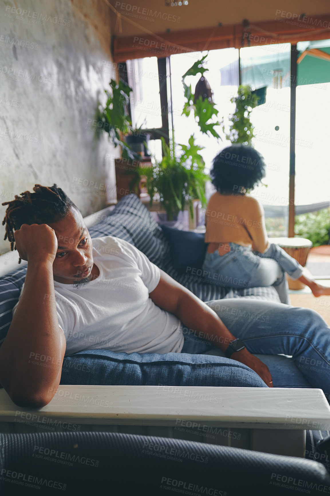 Buy stock photo Shot of a young man looking upset after an argument with his partner at home