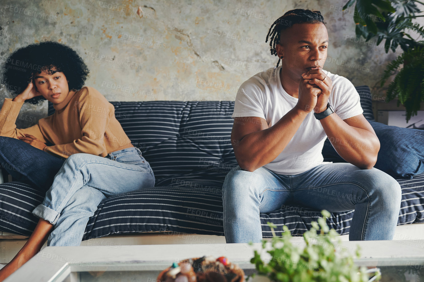 Buy stock photo Shot of a young couple ignoring each other after an argument at home