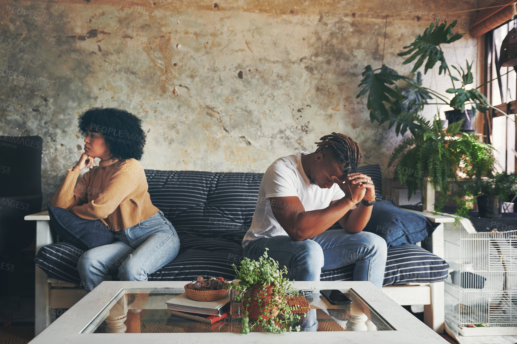 Buy stock photo Shot of a young couple ignoring each other after an argument at home