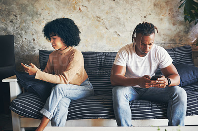 Buy stock photo Shot of a young couple using their cellphones at home