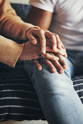 Buy stock photo Closeup shot of an unrecognisable couple holding hands while sitting together on a sofa at home