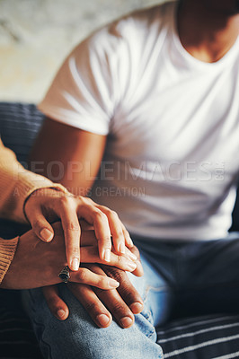 Buy stock photo Closeup shot of an unrecognisable couple holding hands while sitting together on a sofa at home