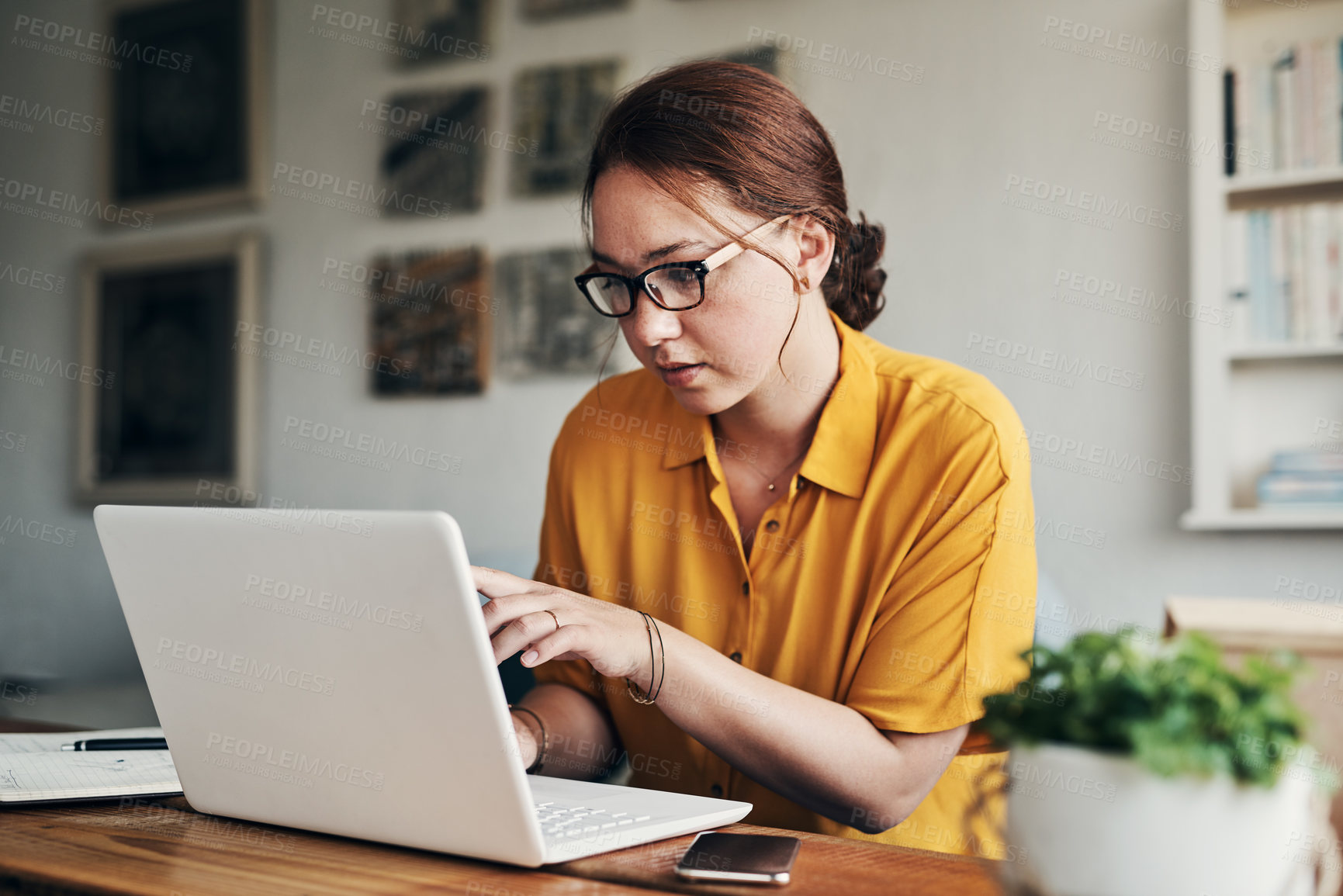 Buy stock photo Shot of a young woman using a laptop while working from home