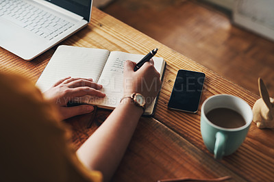 Buy stock photo Shot of an unrecognisable woman writing in a notebook while working from home