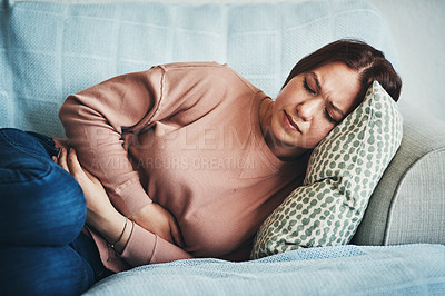 Buy stock photo Stomach ache, pain and woman on home sofa with menstrual or period cramps in lounge. Sick, abdomen or colon problem of a female person with hands on tummy for constipation, digestion or virus