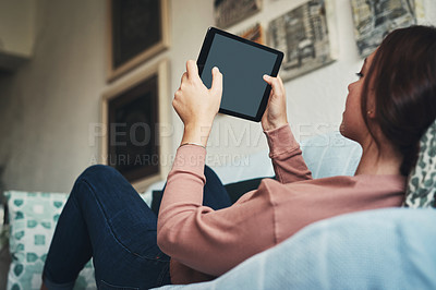 Buy stock photo Shot of a young woman using a digital tablet while relaxing at home