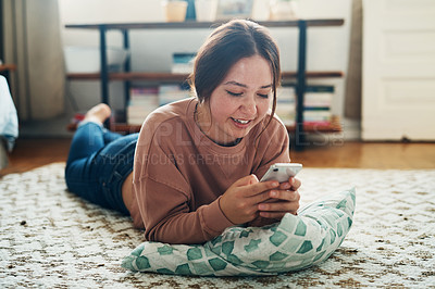 Buy stock photo Shot of a young woman using a smartphone while relaxing at home