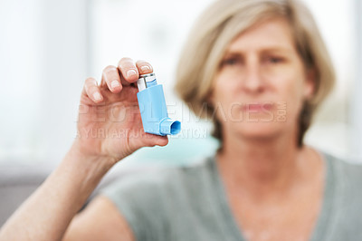 Buy stock photo Shot of a senior holding an asthma inhaler at home