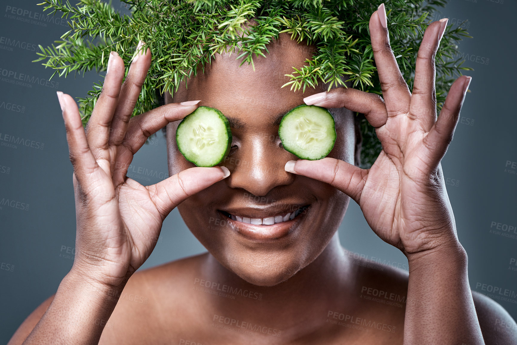 Buy stock photo Shot of a woman holding cucumber slices over her eyes while wearing a leaf wreath