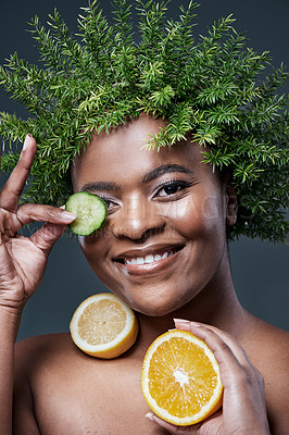 Buy stock photo Shot of a woman wearing a leaf wreath while holding cucumber, lemon and an orange against her skin