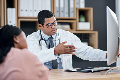 Buy stock photo Shot of a doctor using a computer while having a consultation with a patient