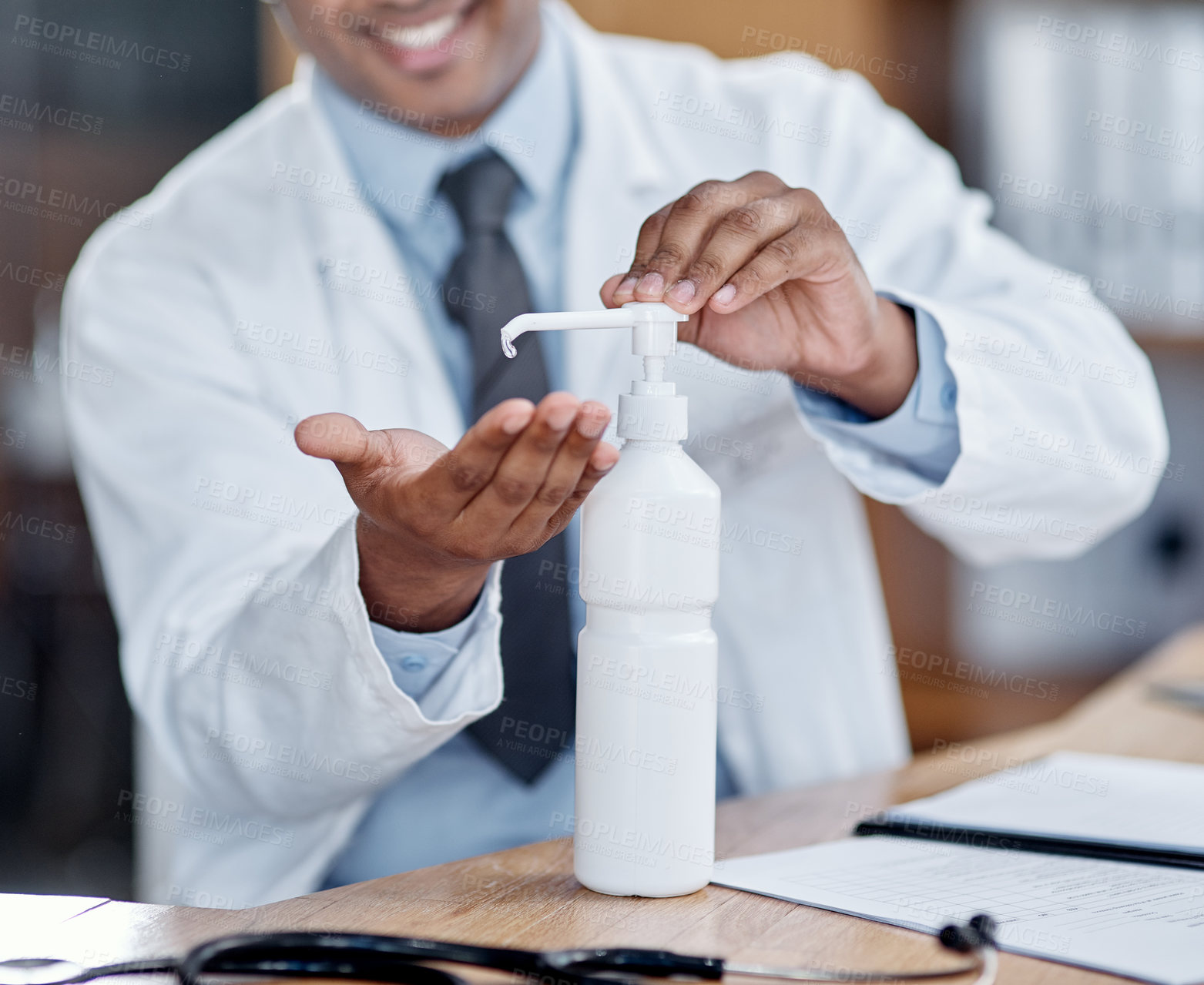 Buy stock photo Closeup shot of an unrecognisable doctor using hand sanitiser while working in his office