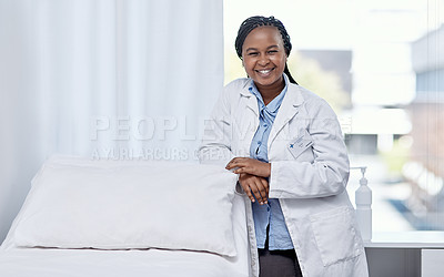 Buy stock photo Happy doctor leaning on a hospital bed smiling, standing and ready to serve, assist and help you get healthy. Cheerful, friendly and young medical professional inside an emergency healthcare facility