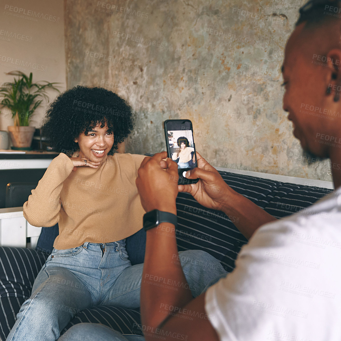 Buy stock photo Shot of a young woman posing while her boyfriend takes photos at home