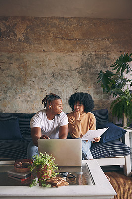 Buy stock photo Shot of a young couple going through paperwork while using a laptop together at home
