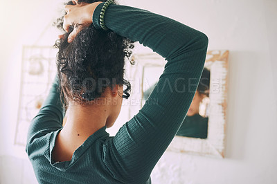 Buy stock photo Rearview shot of a young woman tying her hair in the bathroom at home