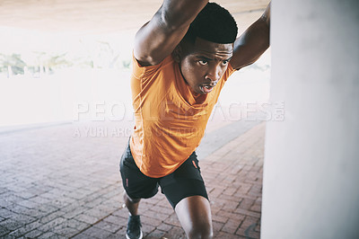 Buy stock photo Shot of a young man stretching during a workout against an urban background