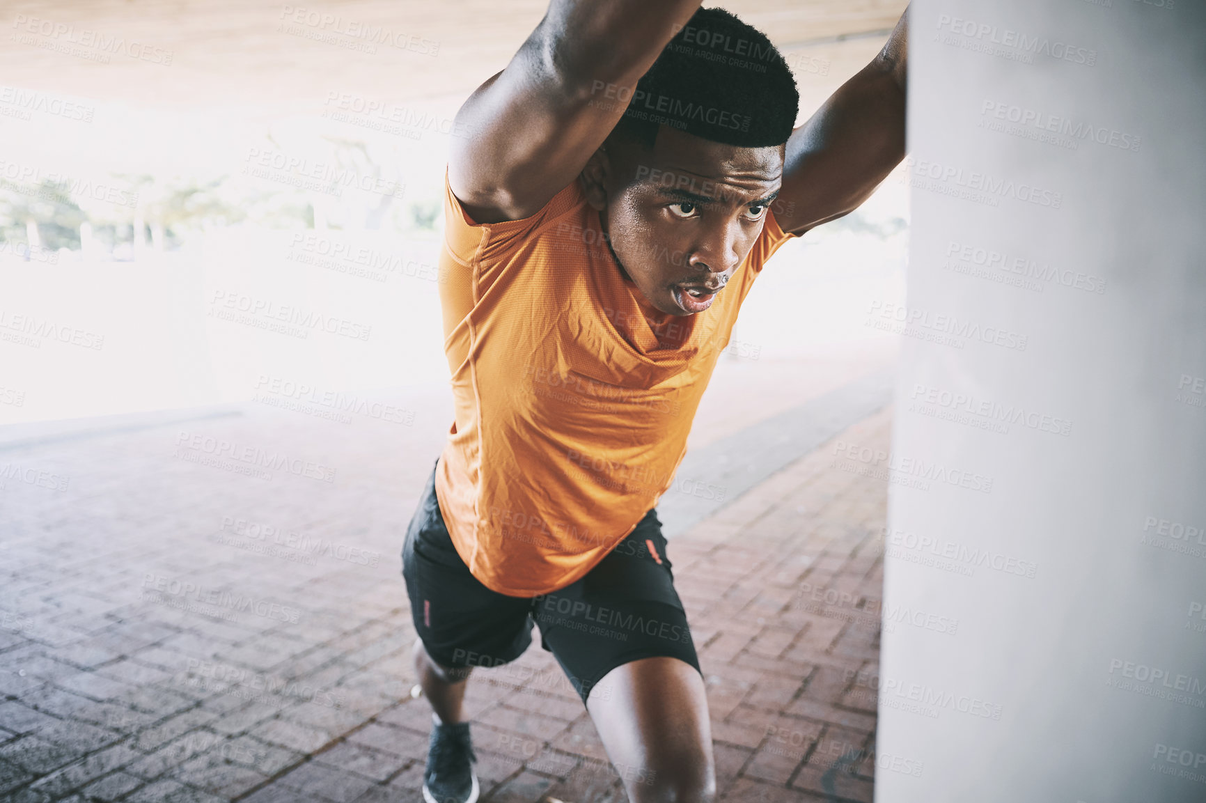 Buy stock photo Shot of a young man stretching during a workout against an urban background