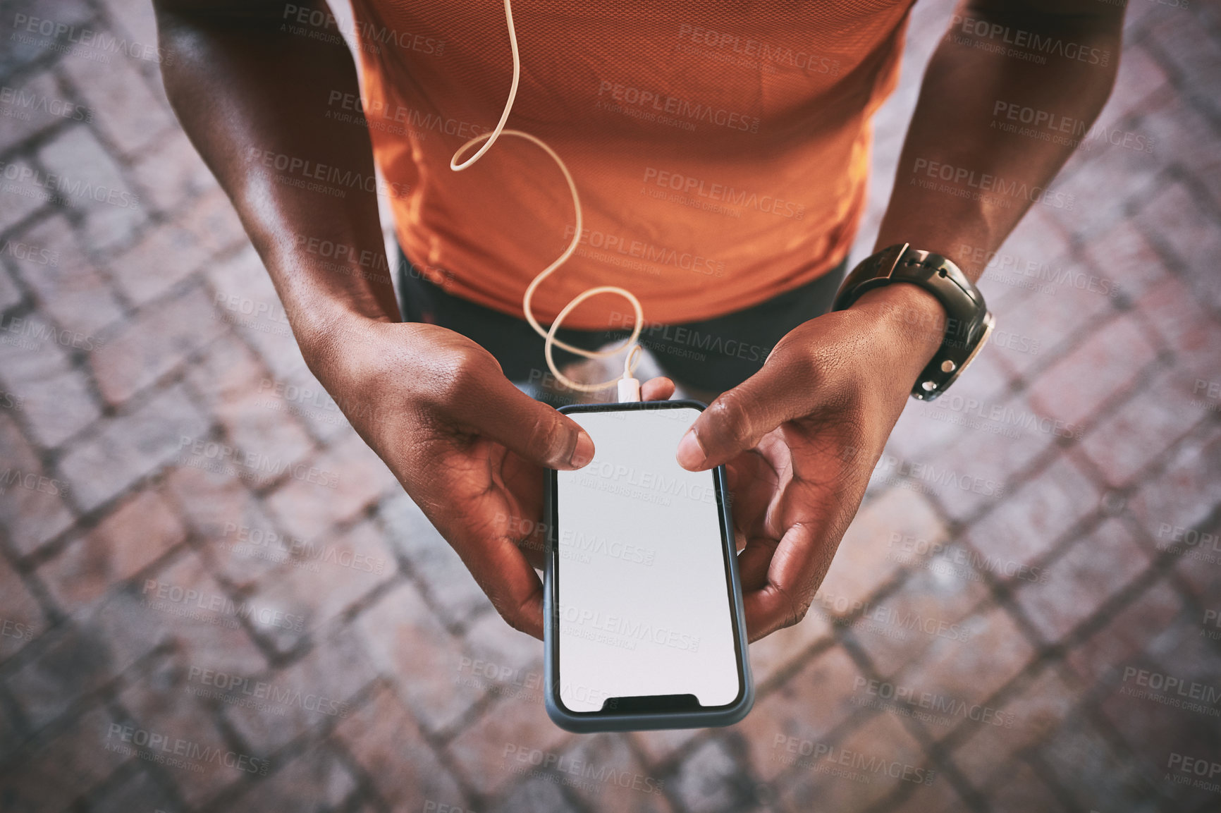 Buy stock photo Cropped shot of a man using a smartphone and earphones during a workout against an urban background