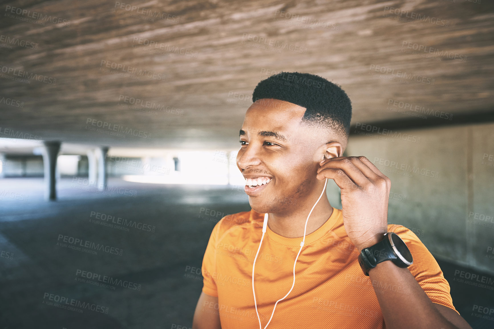 Buy stock photo Shot of a young man using earphones during his workout against an urban background