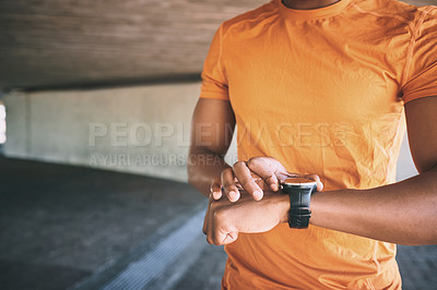 Buy stock photo Cropped shot of a man looking at his watch during a workout against an urban background