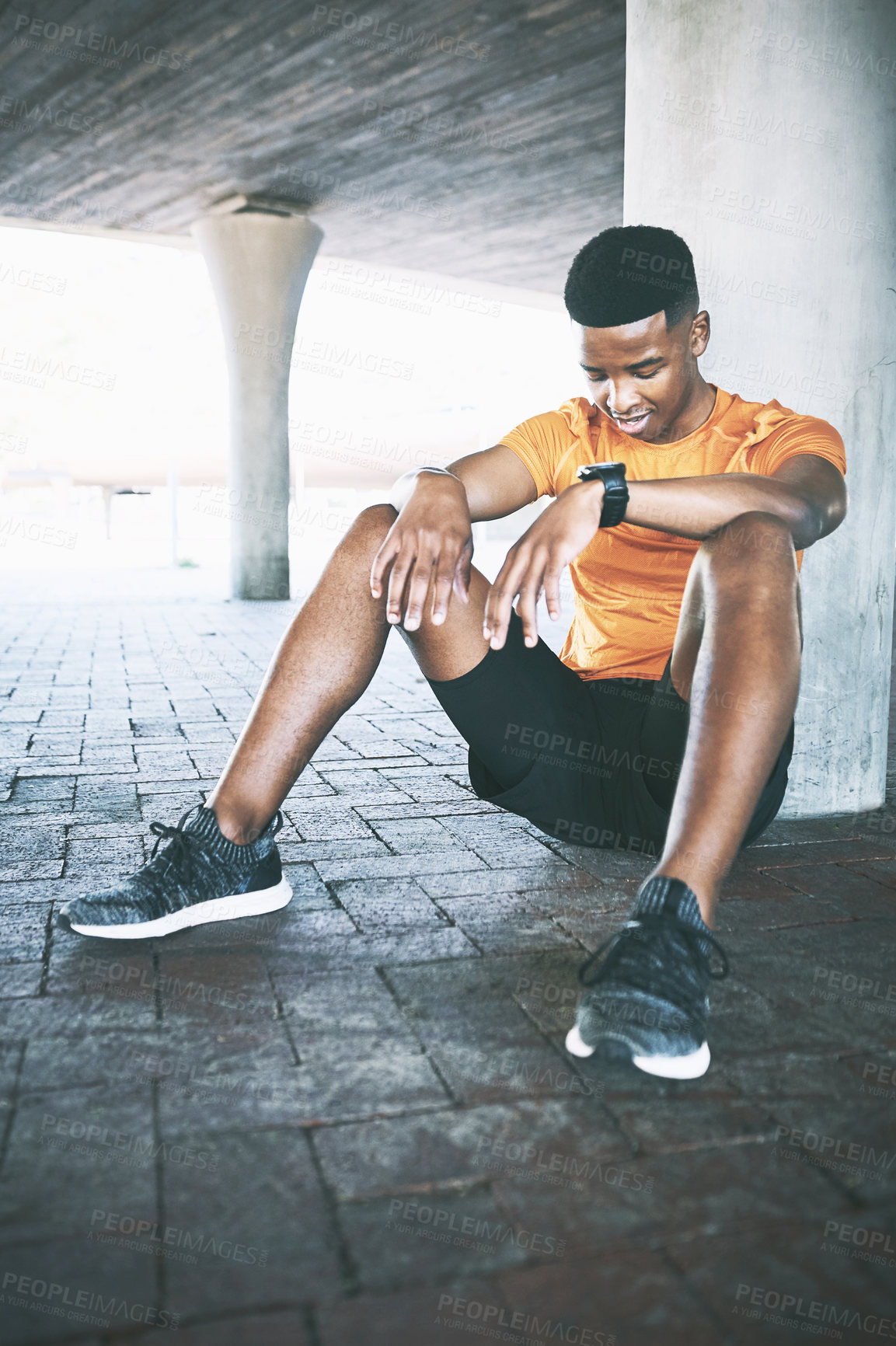 Buy stock photo Shot of a young man taking a break after his workout against an urban background