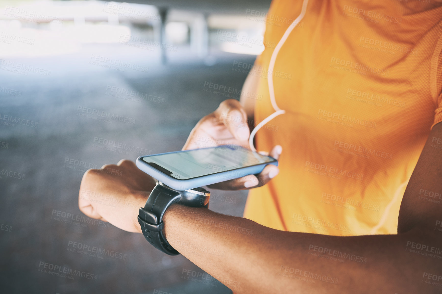 Buy stock photo Shot of a man pairing his watch with a smartphone during a workout against an urban background