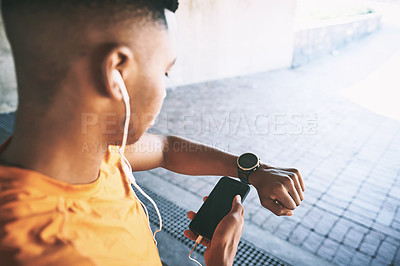 Buy stock photo Shot of a man pairing his watch with a smartphone during a workout against an urban background